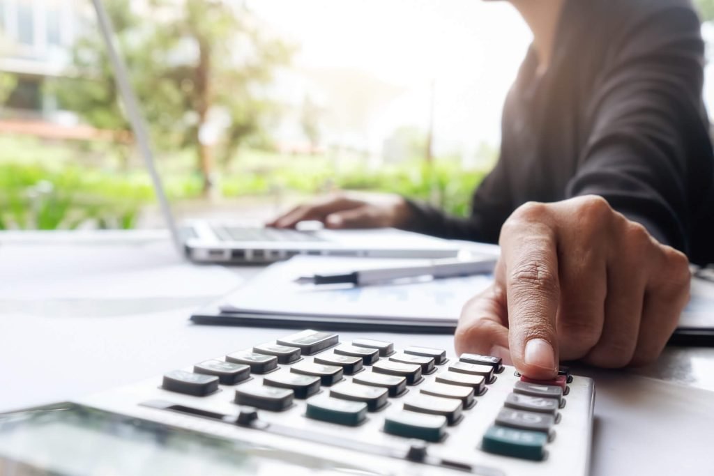 Accountant working through figures on a calculator beside a laptop